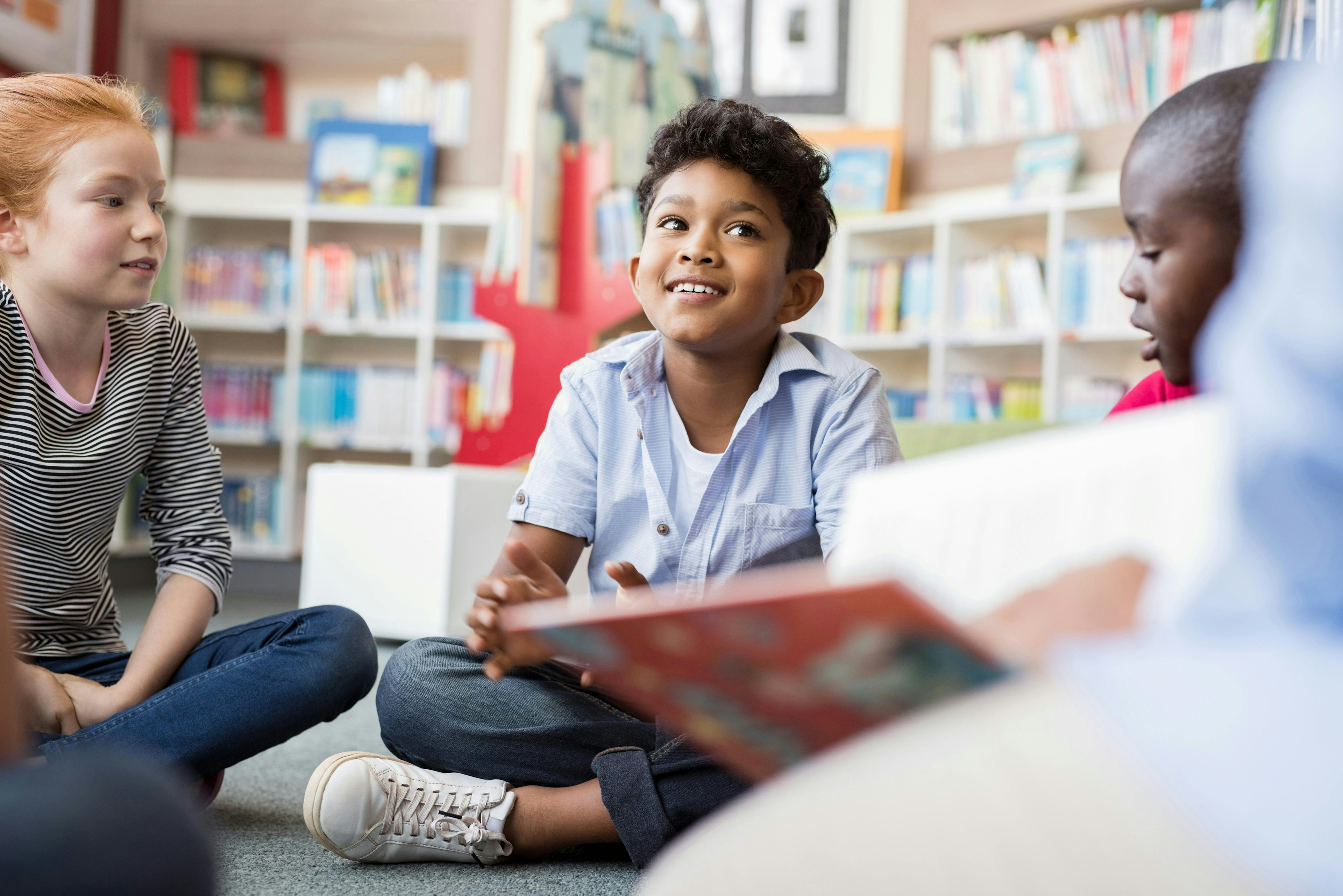 Crianças na escola ouvindo o professor lendo um livro