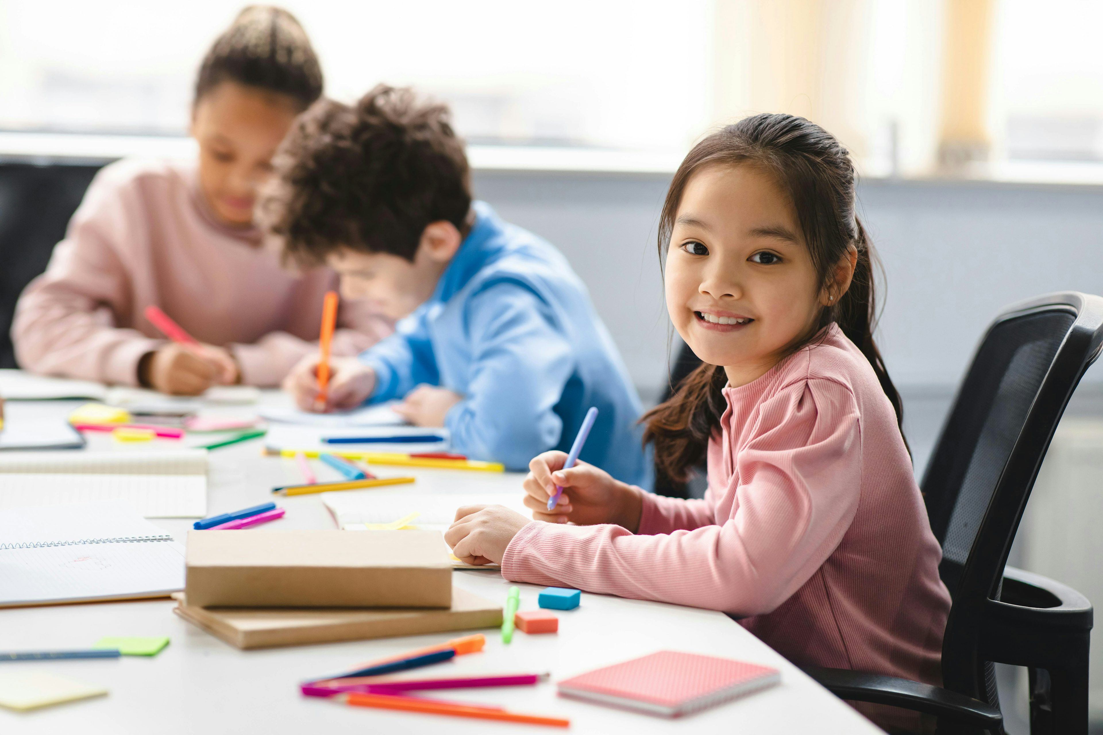 Children sat at a desk with colouring pencils